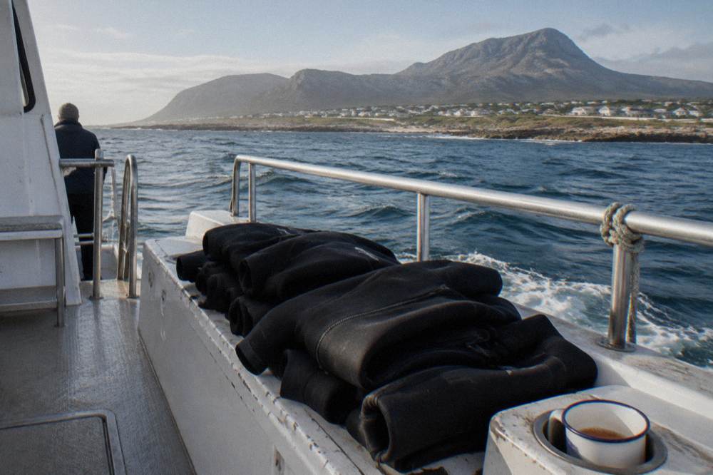 A dive boat deck with a stack of rolled wetsuits and a view of open ocean swell