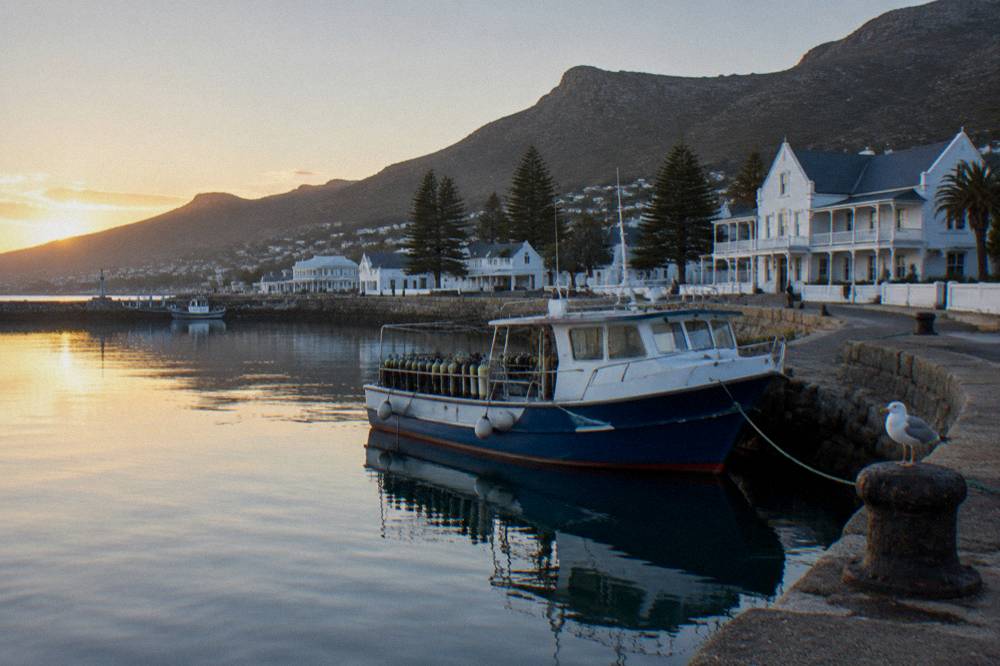 A dive boat moored at a small harbour jetty at first light with calm water