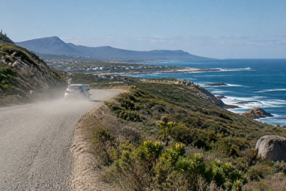 A coastal road winding along cliffs above the ocean on the drive toward Gansbaai