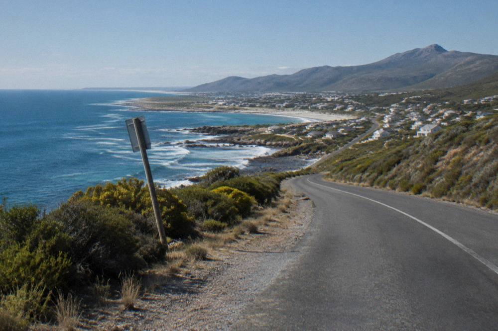A coastal road winding along cliffs with the ocean on the left in morning light