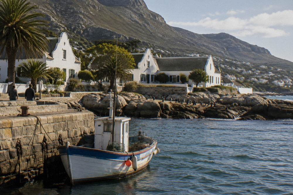 A small boat moored at a False Bay harbour with a coastal town behind it