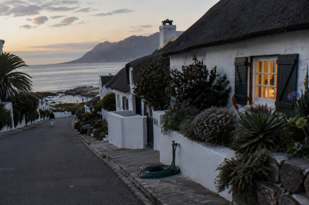 A quiet coastal village street in early evening light with the sea in the distance