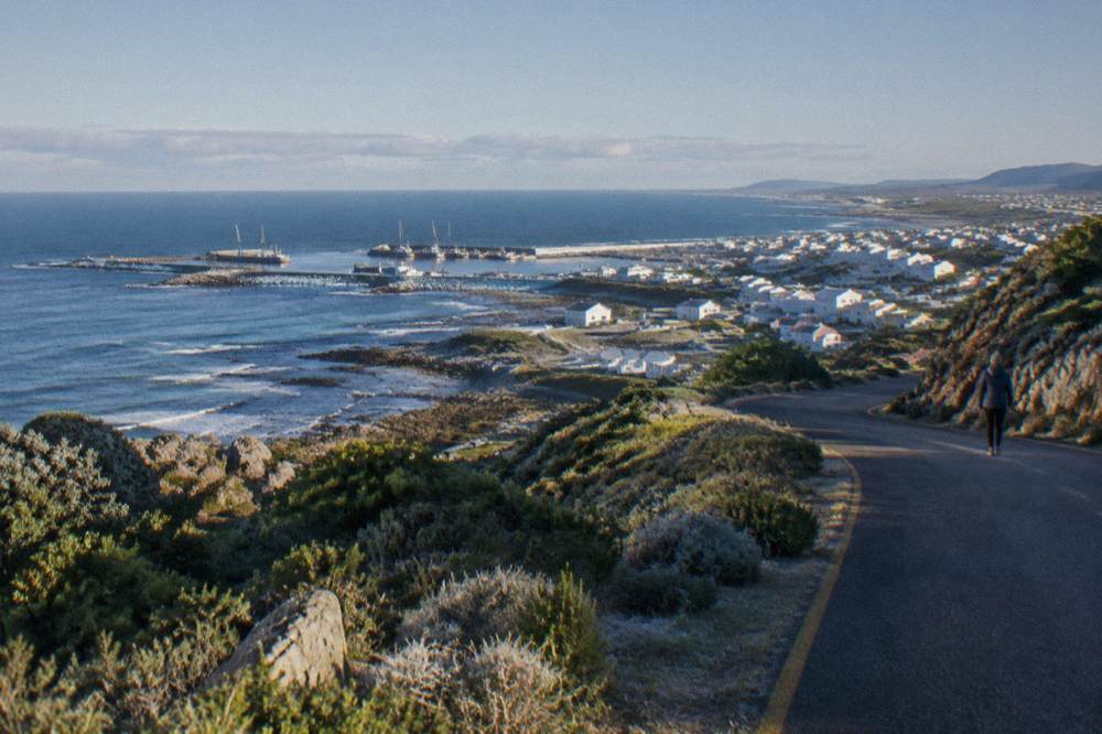 Coastal road winding along cliffs toward a small Overberg fishing town