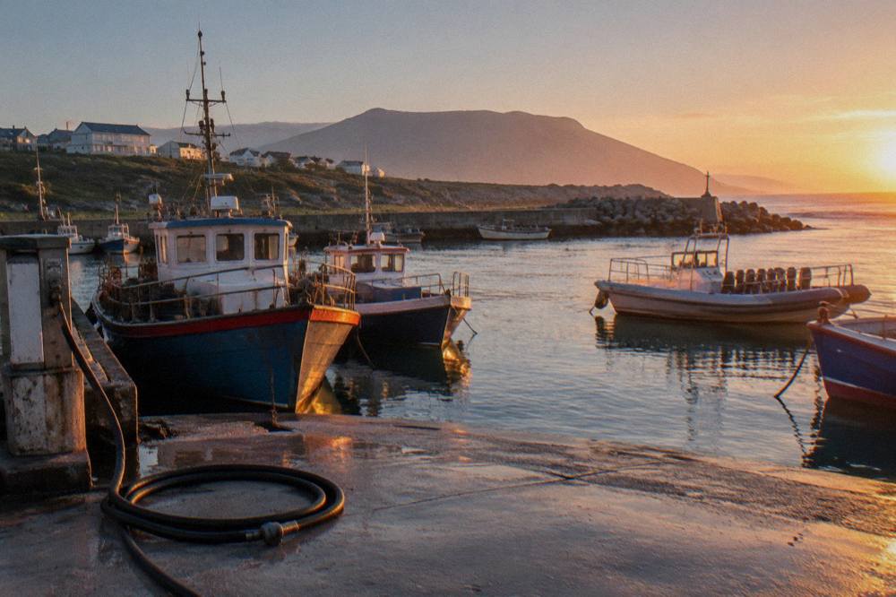 Small fishing harbour with tour boats moored at a concrete slipway at sunrise