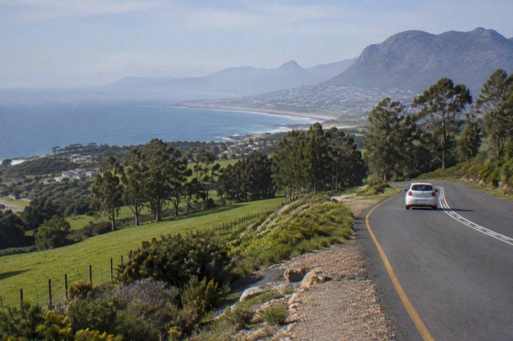Coastal road curving along green hills above the ocean