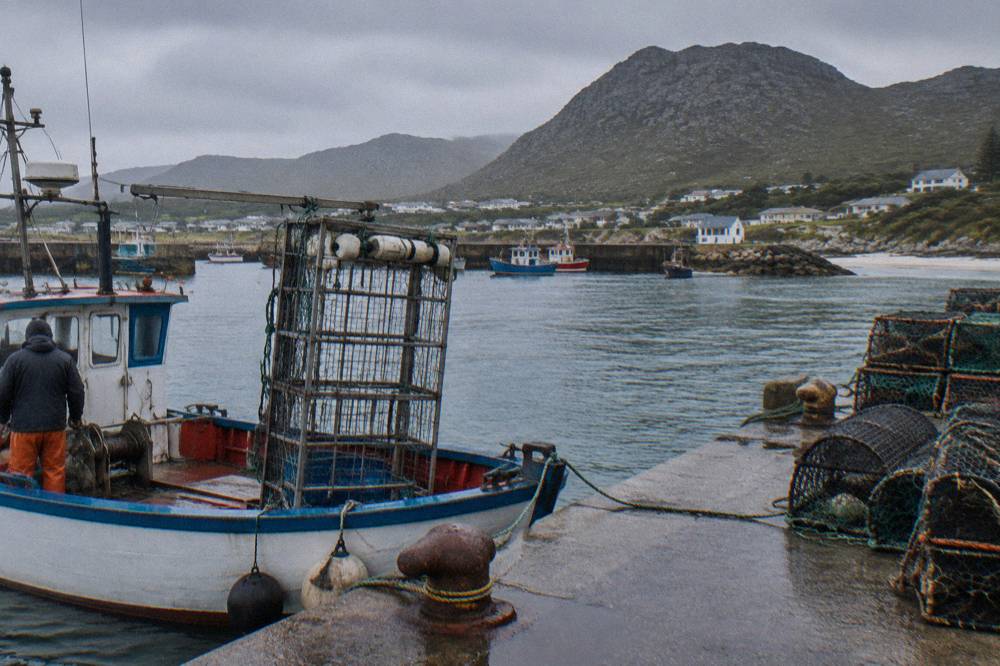 A shark cage mounted alongside a dive boat at a small working harbour
