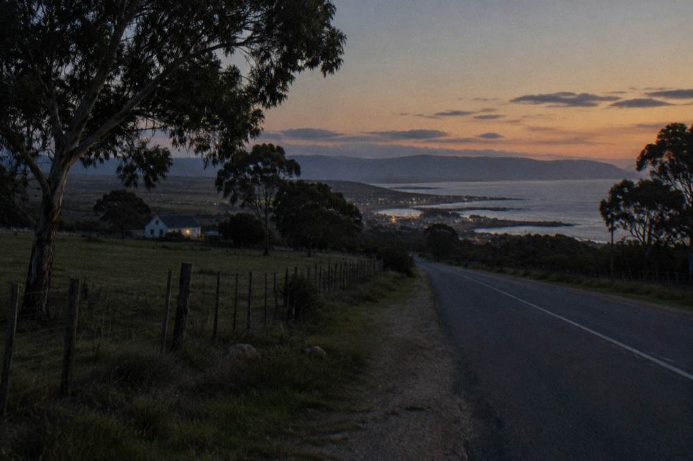 Quiet coastal road through farmland towards a small harbour town