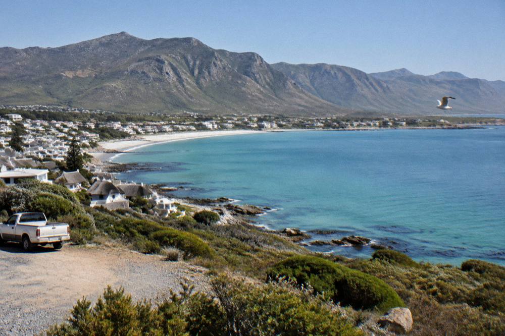 A small coastal town at midday with a curving bay and calm water